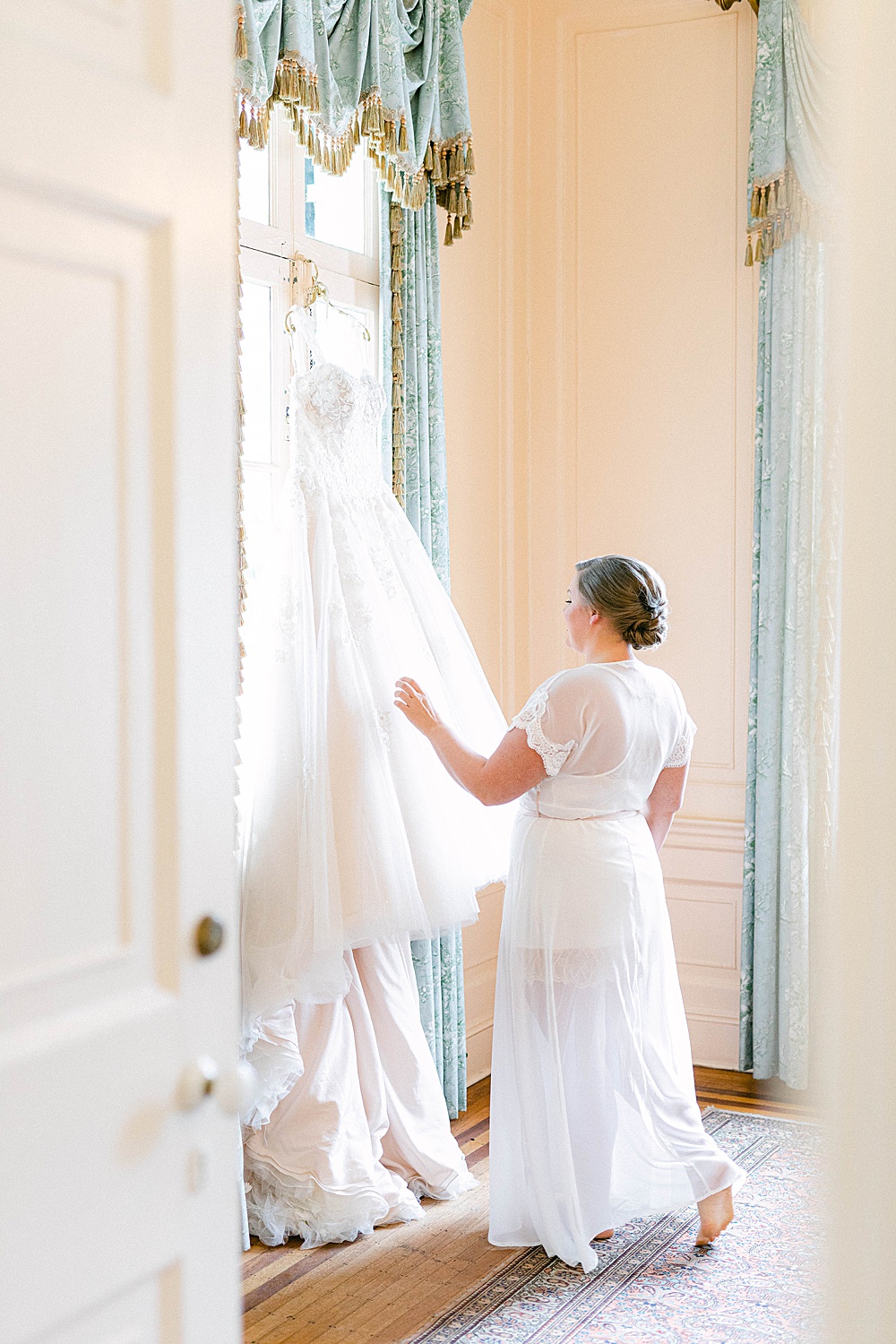bride touching her wedding dress in a room at Lowndes Grove Plantation