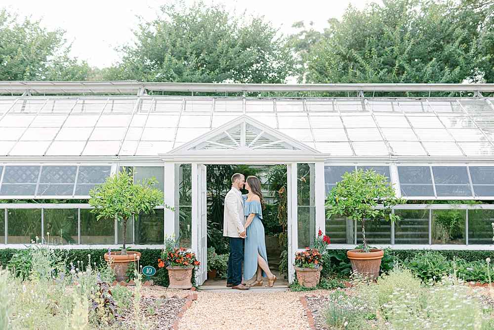 Couple posing in front of the greenhouse at Hills & Dales Estate