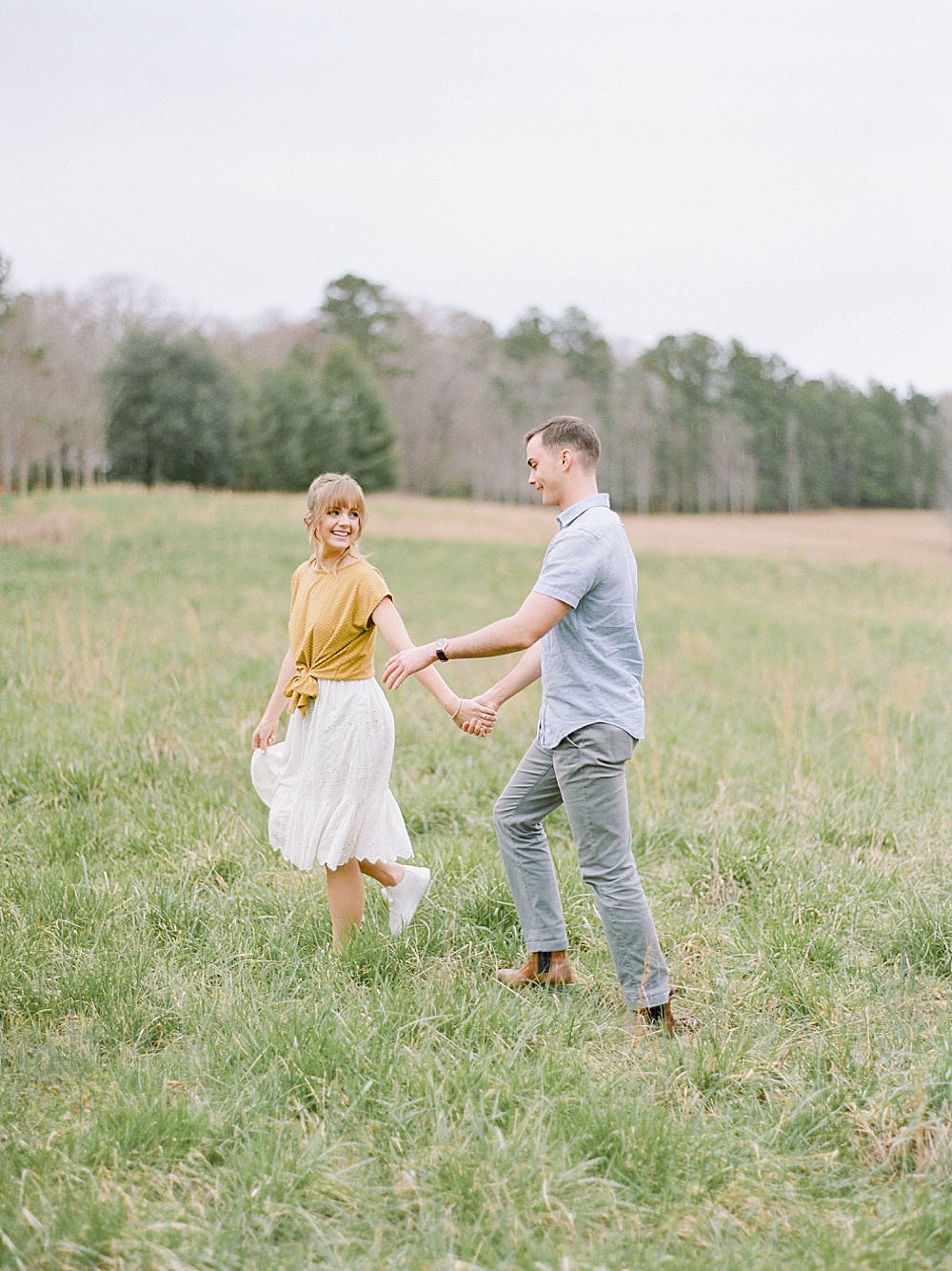 girl leading a guy through a field