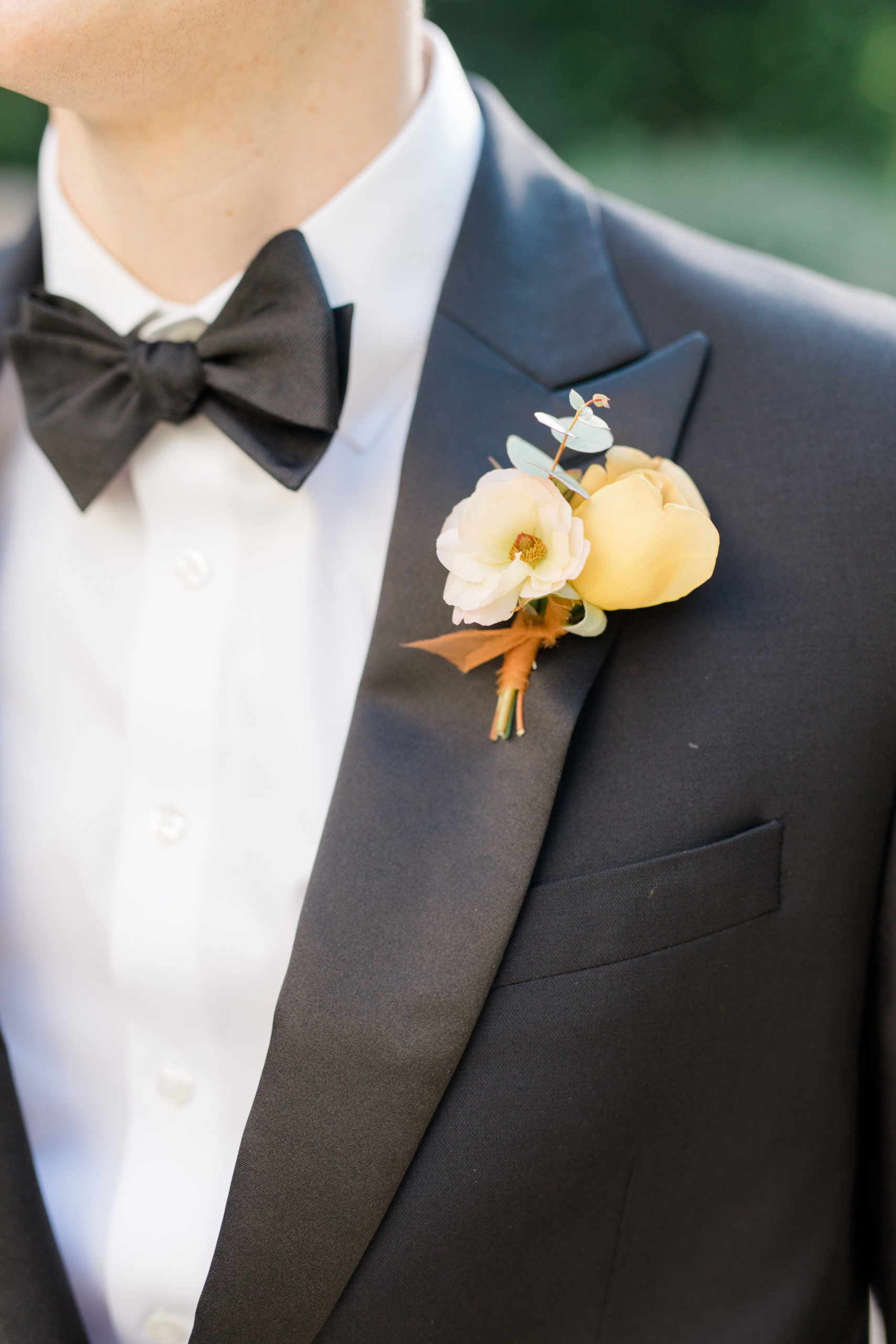 white, yellow and orange boutonniere on a black tuxedo with bow tie