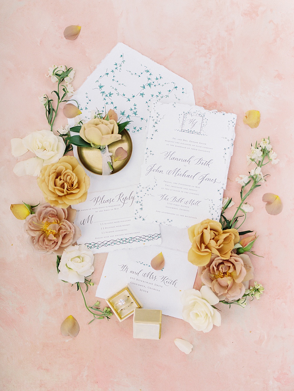 Hand torn invitation suite on a pink styling mat with yellow and blush flowers