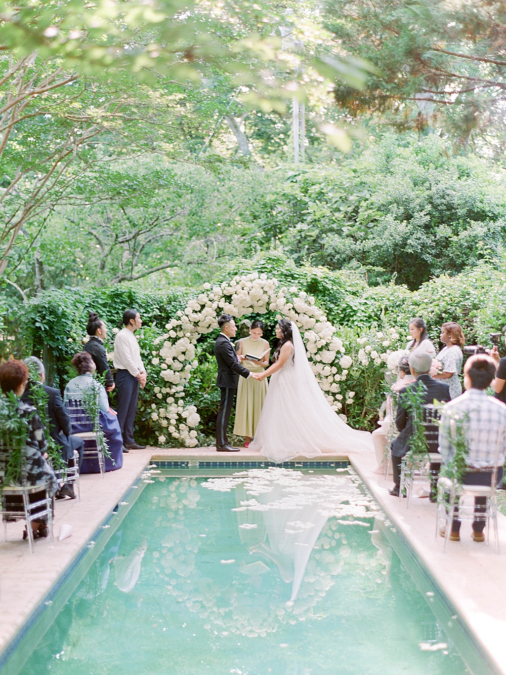 Wedding ceremony at a reflection pool at Meadowlark 1939 with a white floral arch