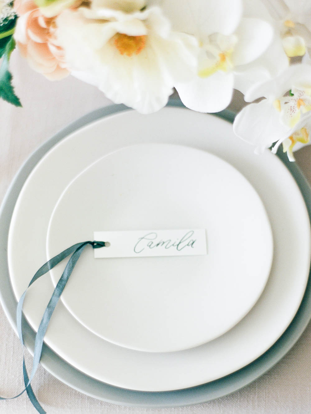 Name card on a white place setting with blue ribbon