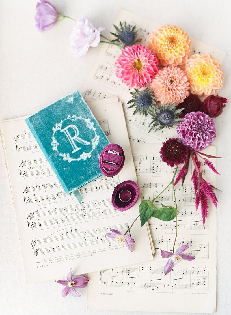 Jewel toned wedding details on sheet music with dahlias