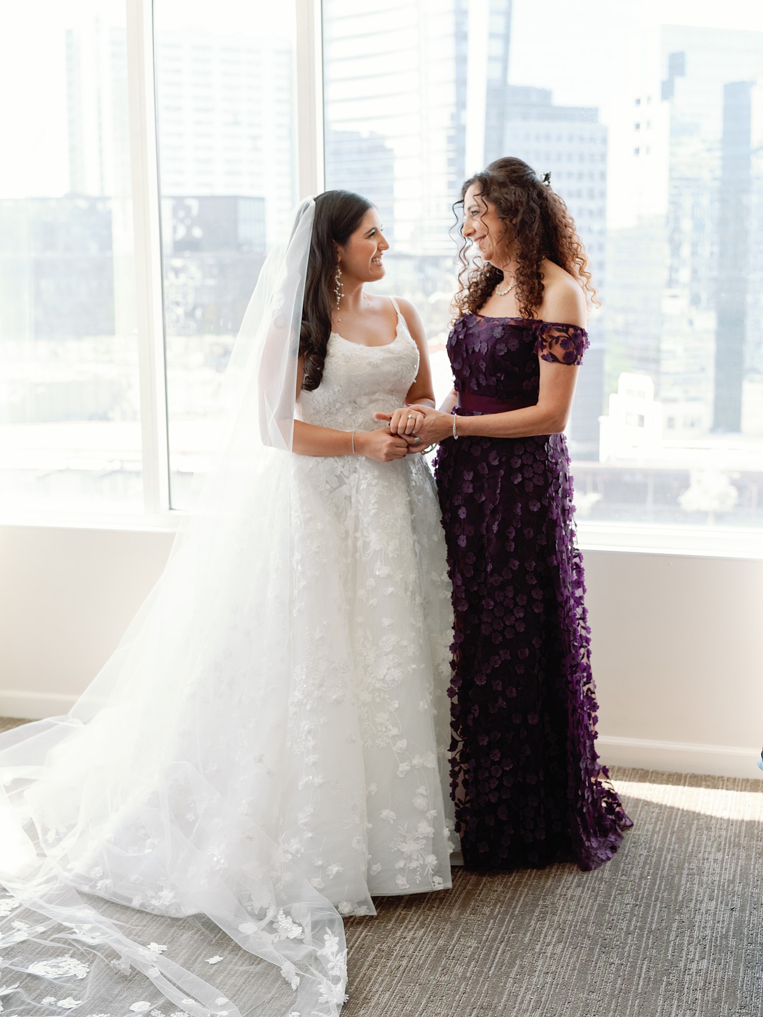 A bride getting ready with her mom in front of windows with the Atlanta skyline in the background