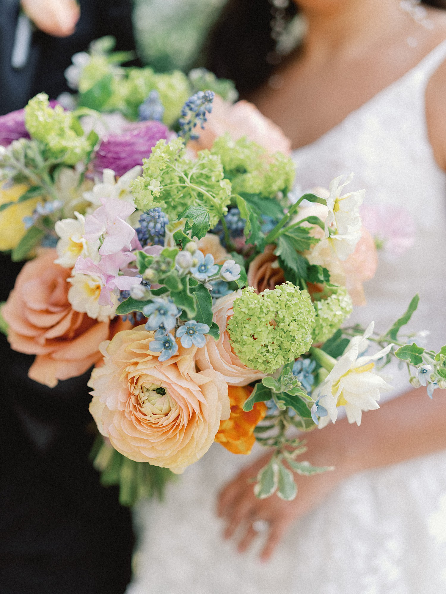 A close up of the bride's florals, including orange roses with blue, green and peach florals.