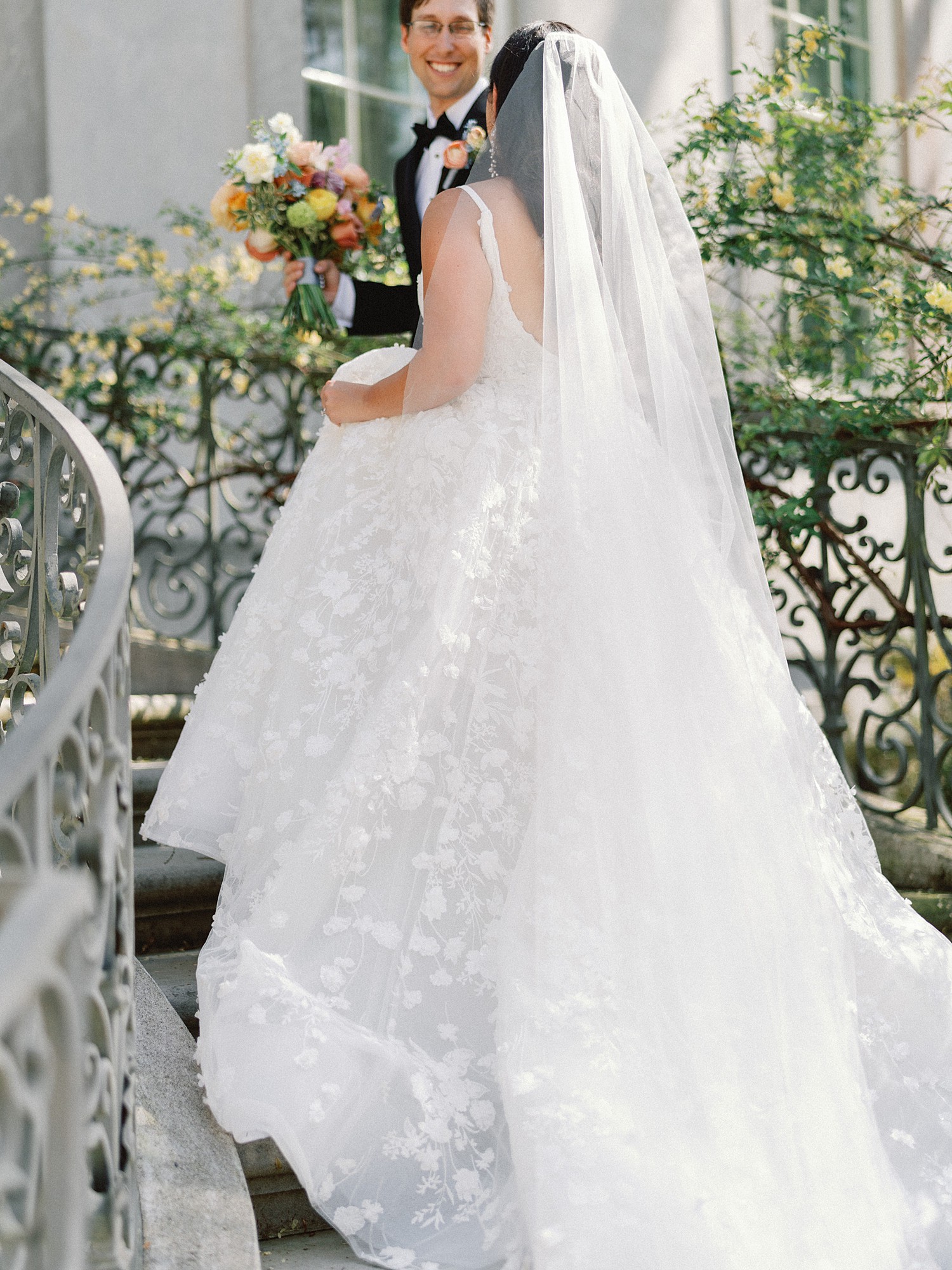 A detail shot of the brides dress from behind as she walks up the Swan House stairs