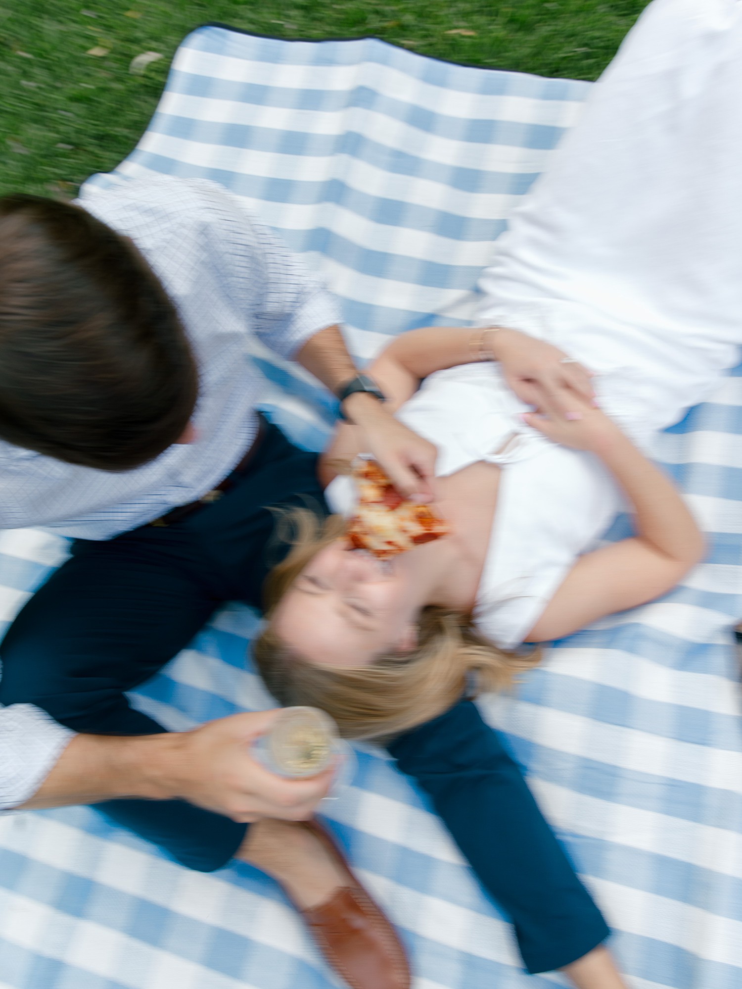 Blurry photo of a man feeding a girl pepperoni pizza while she lays in his lap during a picnic in a park