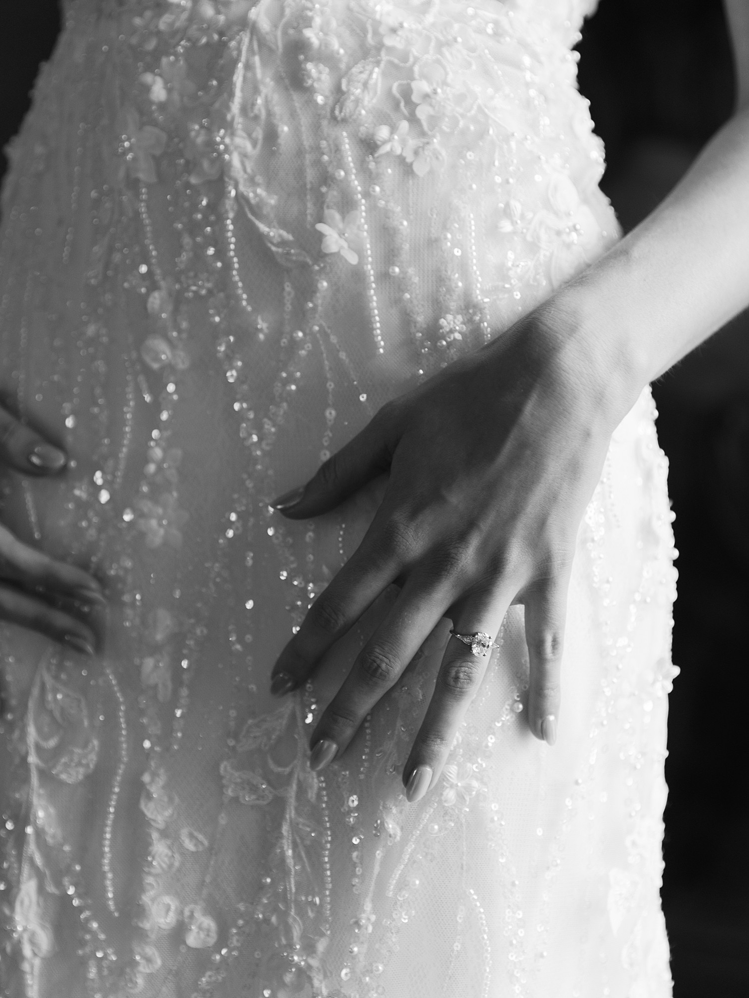 Close up of a bride's hand on her wedding gown in black and white