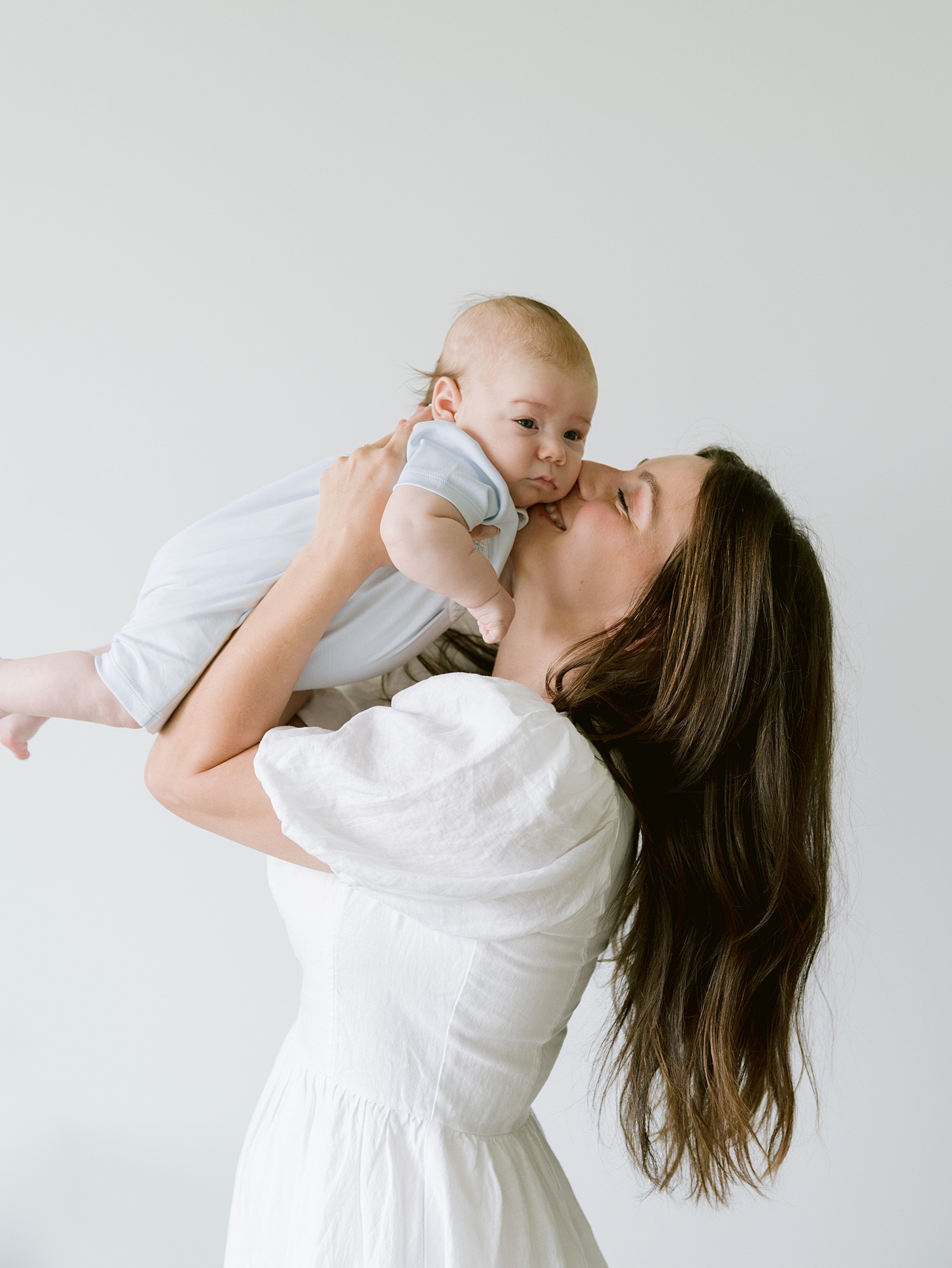 A mom snuggling and holding her boy and kissing his cheek