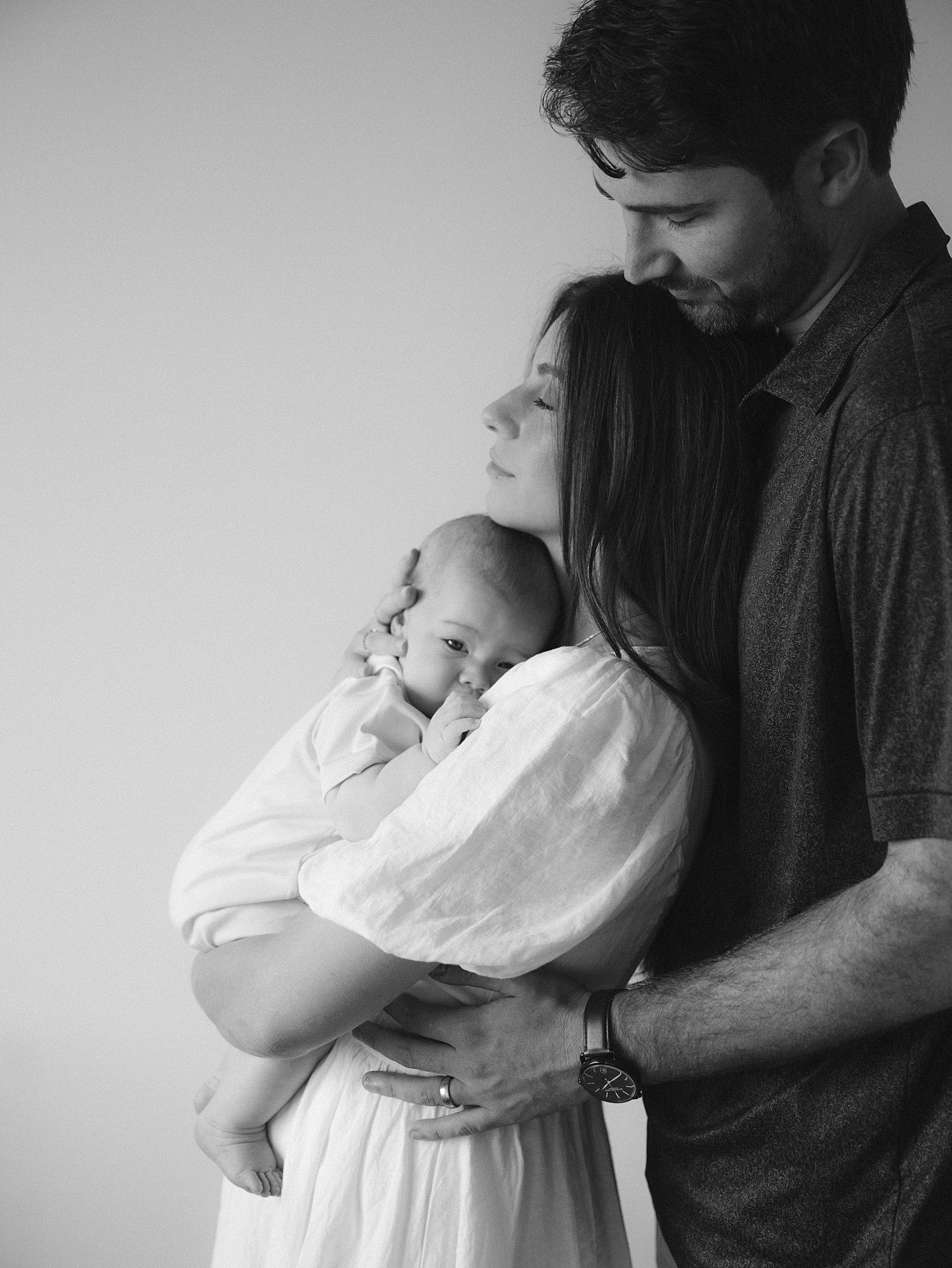 Black and white portrait of a young family in profile with the baby on bottom, mom in the middle, and the dad on top captured by Senoia family photographer, Laura Watson