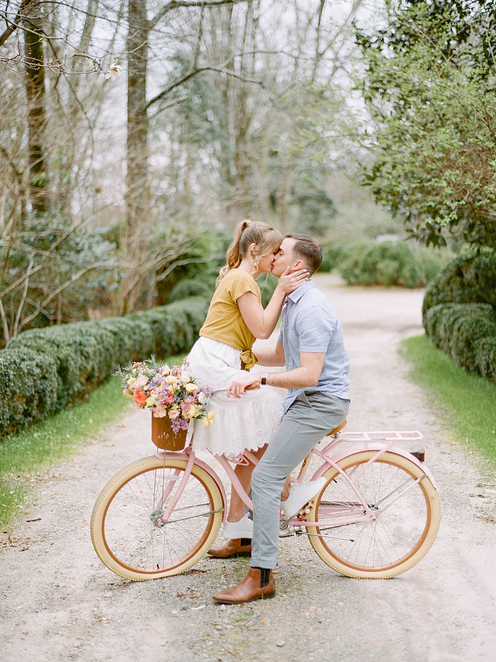 Engaged couple kissing on a pink bicycle at Meadowlark 1939