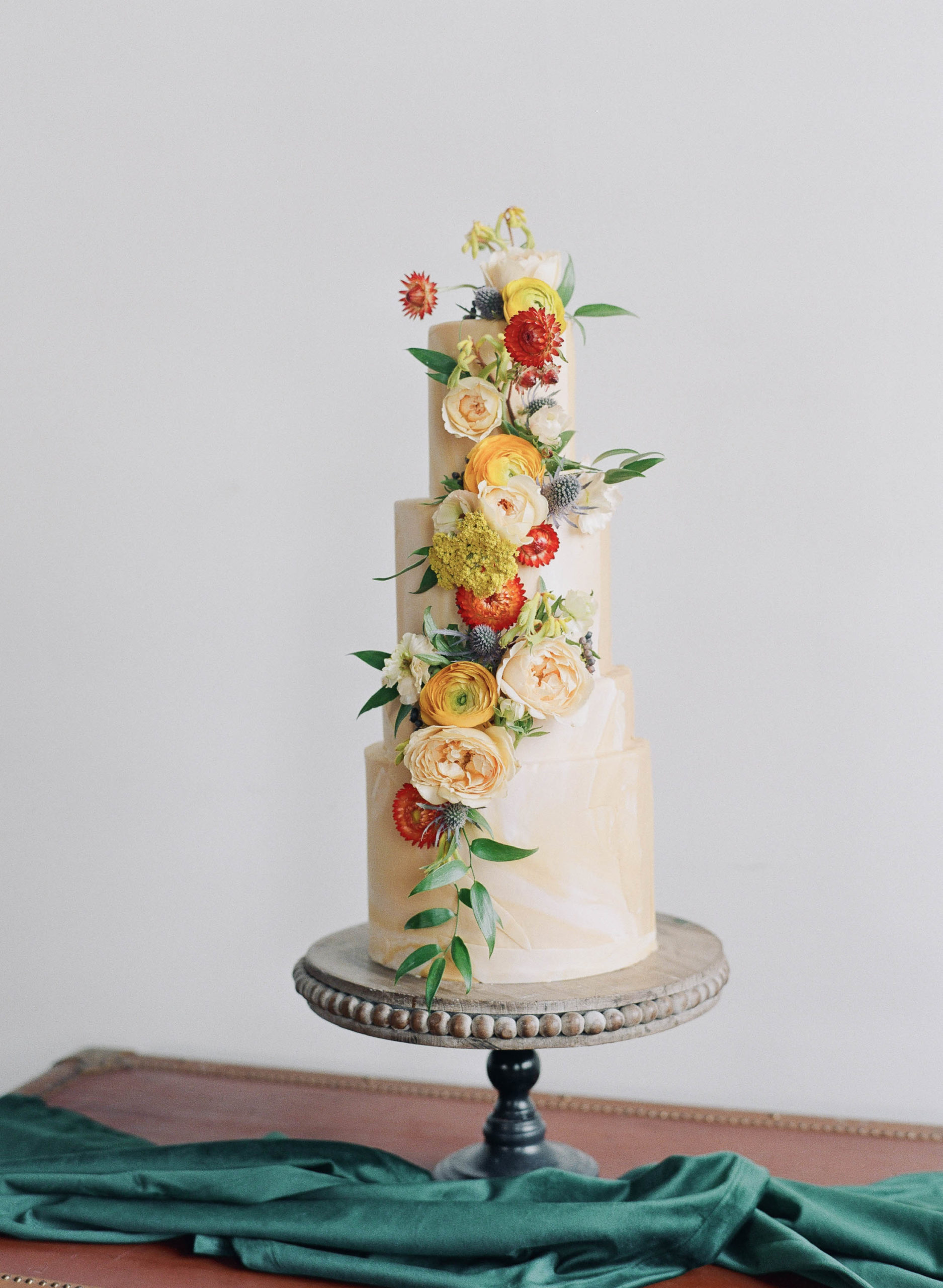 Wedding cake covered in orange, yellow and red flowers