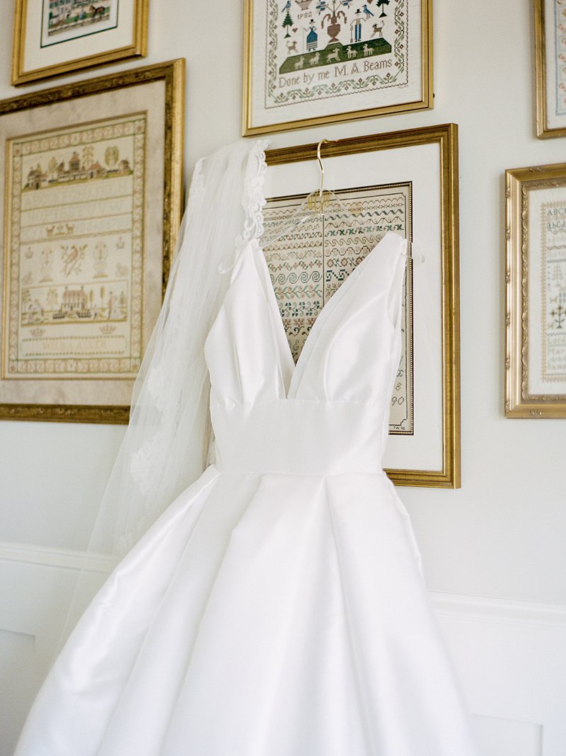 Classic a-line wedding dress hanging on cross stitches in a bride's home