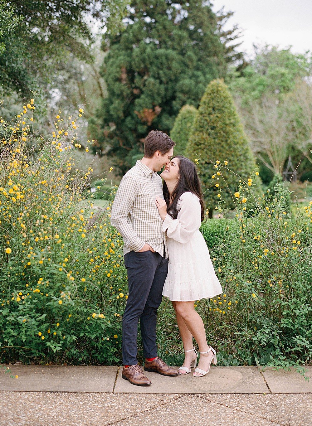 A couple posed in front of yellow flowers at Hills & Dales Estate and Gardens.