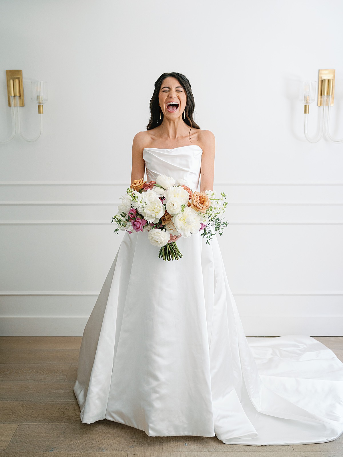 Bride laughing while holding her bouquet in the bridal room at Bishop Station in Atlanta