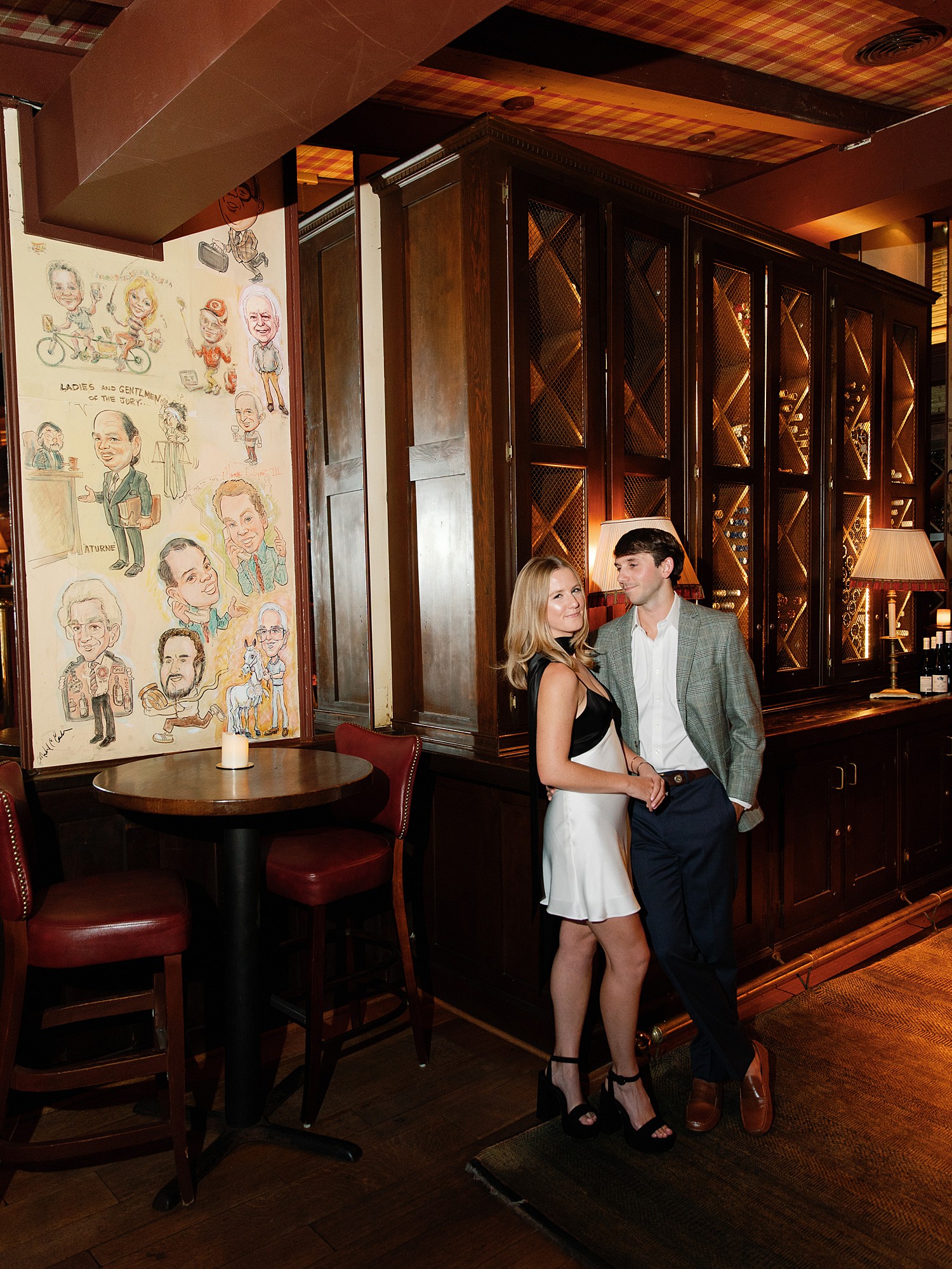 An engaged couple poses in front of the wine display at Bones Restaurant in Atlanta